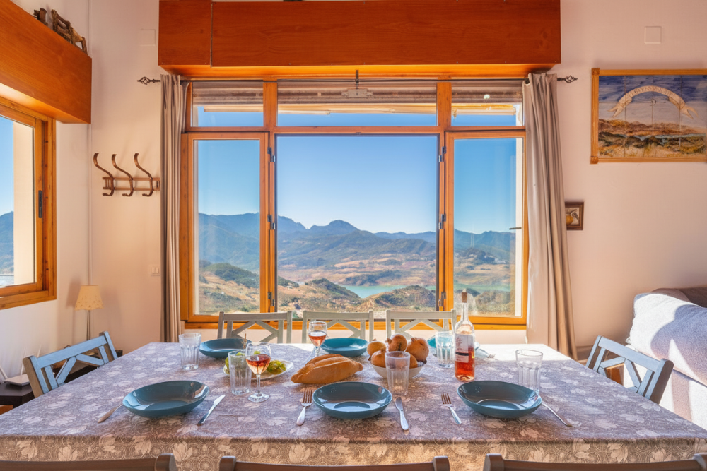 Interior de una casa rural con una gran ventana con vistas al embalse de Zahara-El Gastor